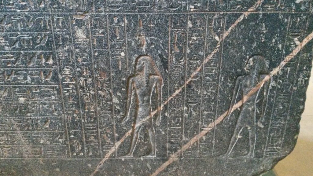 A beautifully carved ancient Egyptian artefact in the British Museum. Two light-colored veins are visible in the rock. 