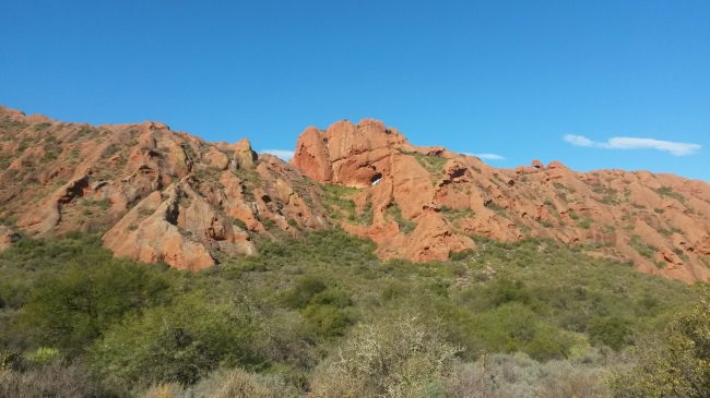 Red conglomerate hills with a rock arch. 